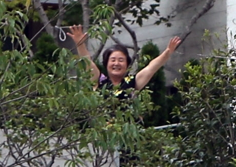 전국에서 온 문재인 전 대통령 지지자들이 17일 낮 문재인 전 대통령 사저가 있는 경남 양산시 하북면 지산리 평산마을에 모여 평산마을 평온 회복과 문 전 대통령 부부 안녕을 기원하는 집회를 했다. 문 전 대통령 부인 김정숙 여사가 사저 바깥으로 잠깐 나와 조경수 사이로 지지자들을 향해 손을 흔들고 있다.   연합뉴스